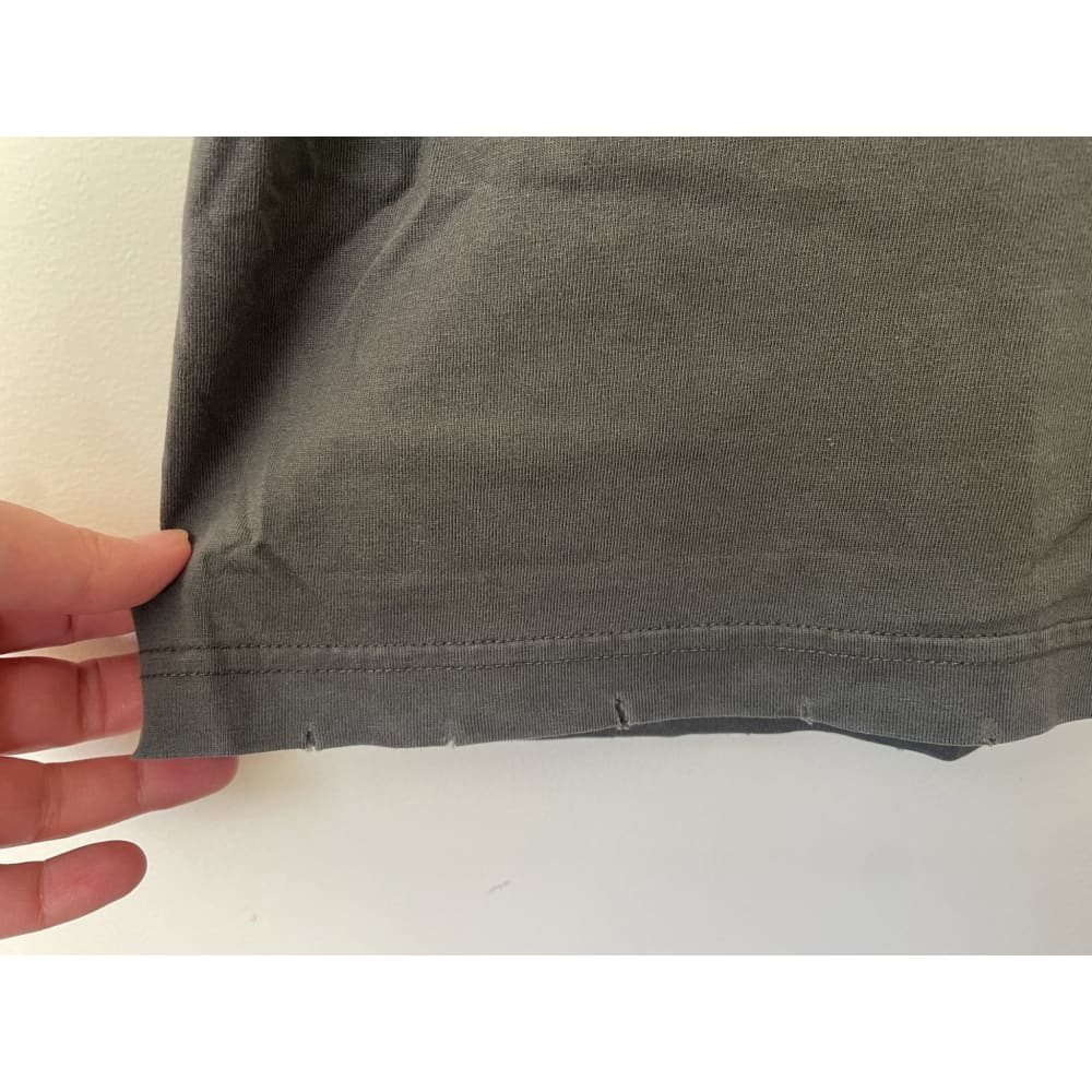 Close-up of a gray cotton shirt hem with small tears.