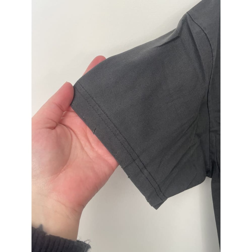 Close-up of a gray T-shirt sleeve held by a hand.
