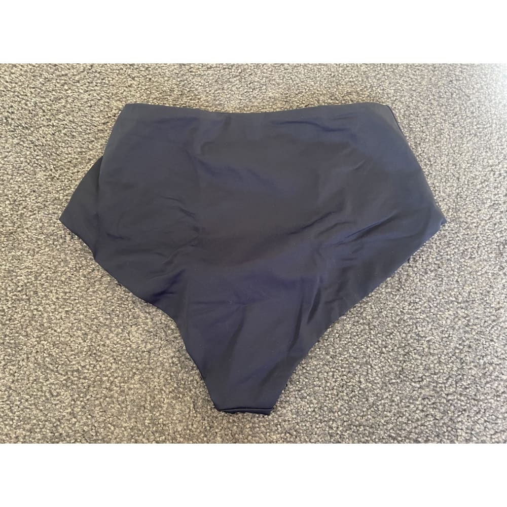 Dark blue high-waisted bathing suit bottom on carpet.