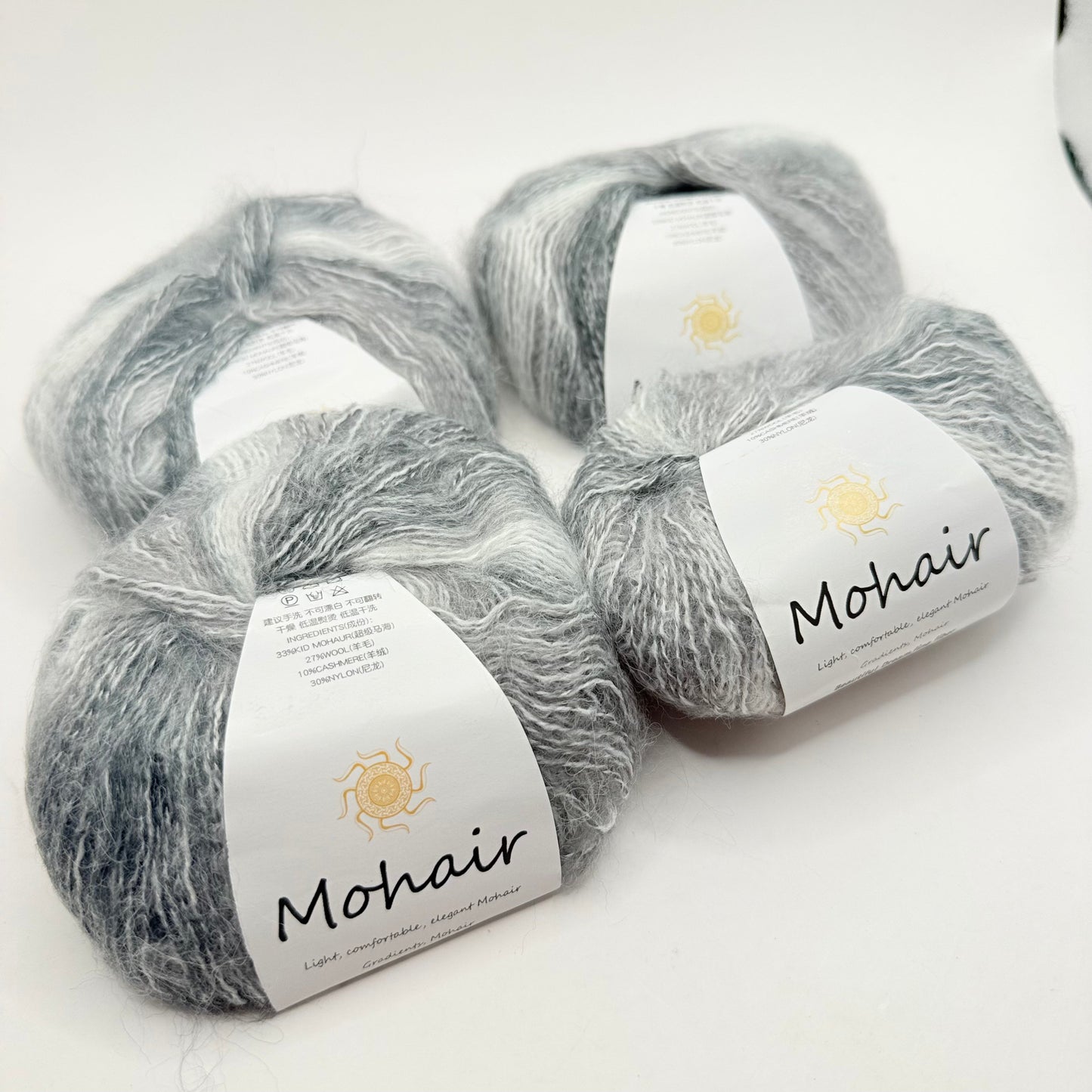 Four skeins of soft, fluffy gray and white variegated mohair yarn.