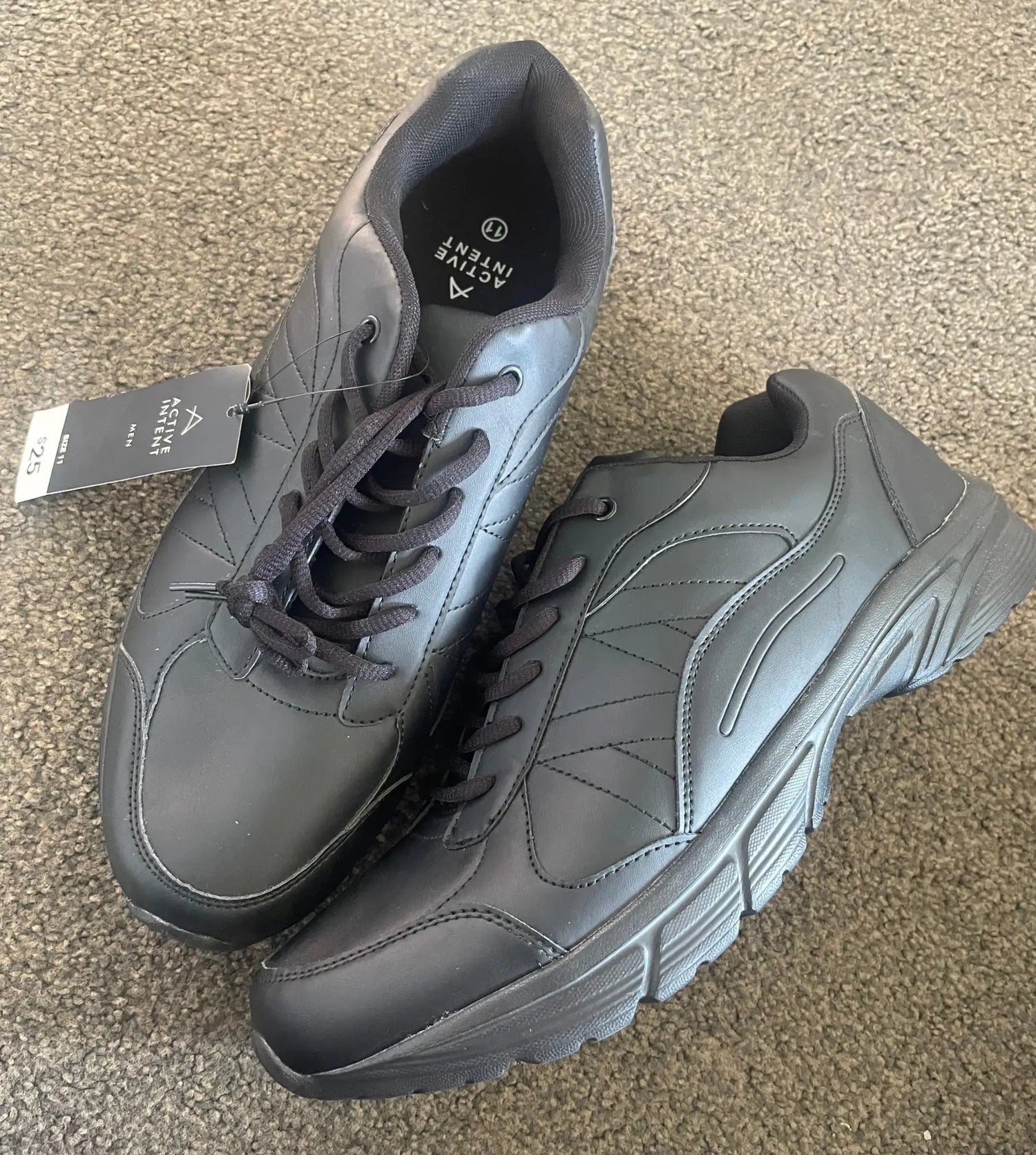 A pair of new black Active Intent athletic shoes with laces and a price tag.