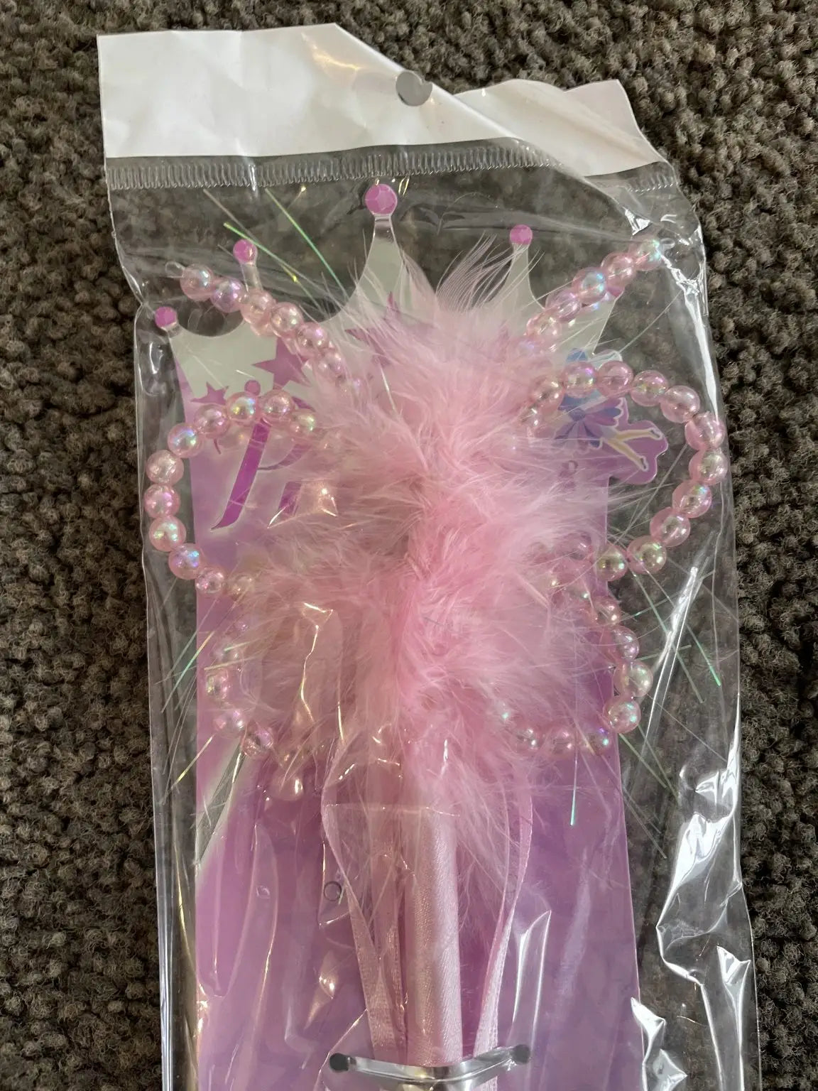 A pink feathered pen with a crown-shaped top and pearl-like beads.