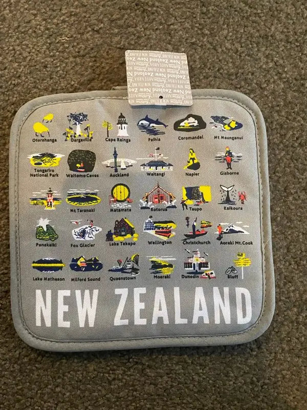 A gray fabric pot holder with colorful illustrations of New Zealand landmarks and cities.