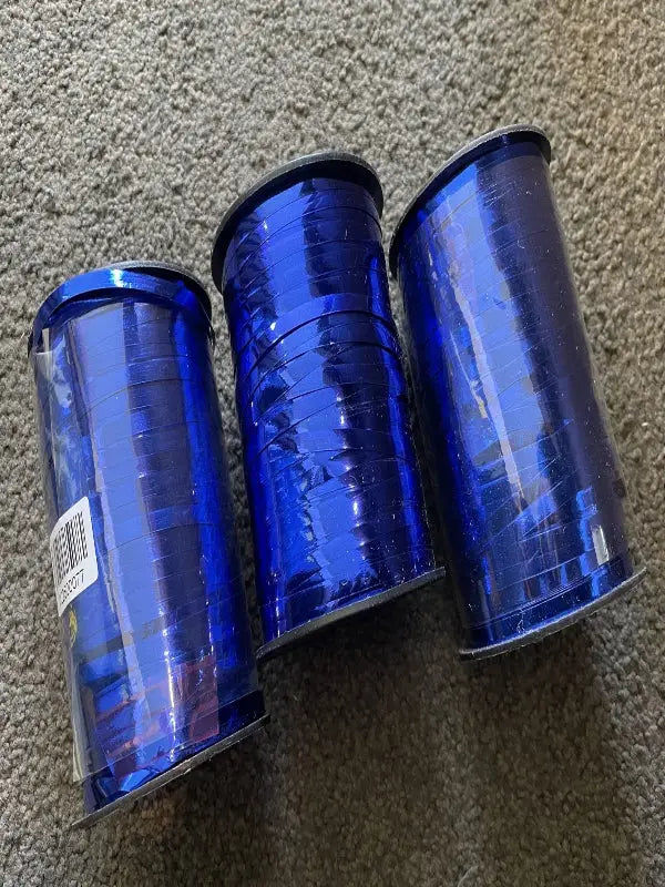 Three spools of shiny blue curling ribbon.