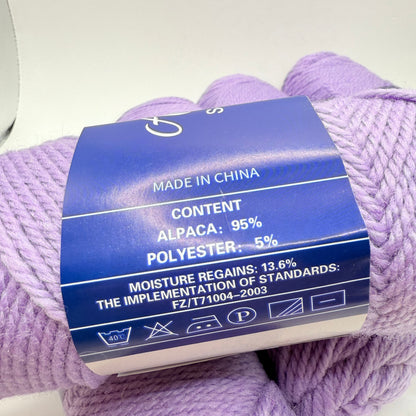 A skein of light purple yarn, 95% alpaca and 5% polyester, with care instructions.