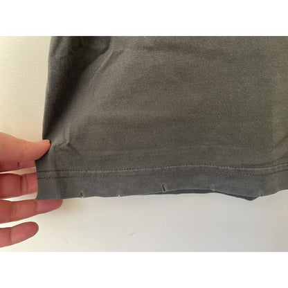 Close-up of a gray cotton shirt hem with small tears.
