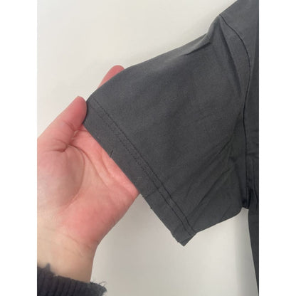 Close-up of a gray T-shirt sleeve held by a hand.