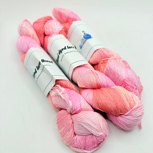 Three skeins of pink and coral ombré dyed lace thread.
