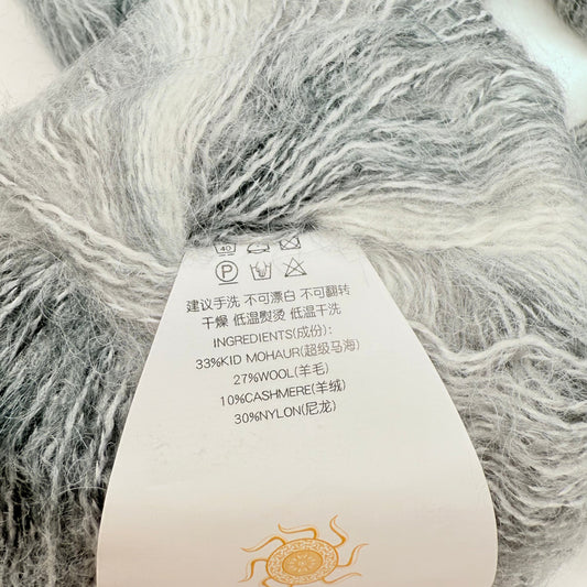A skein of gray and white mottled yarn with a label detailing its fiber content and care instructions.