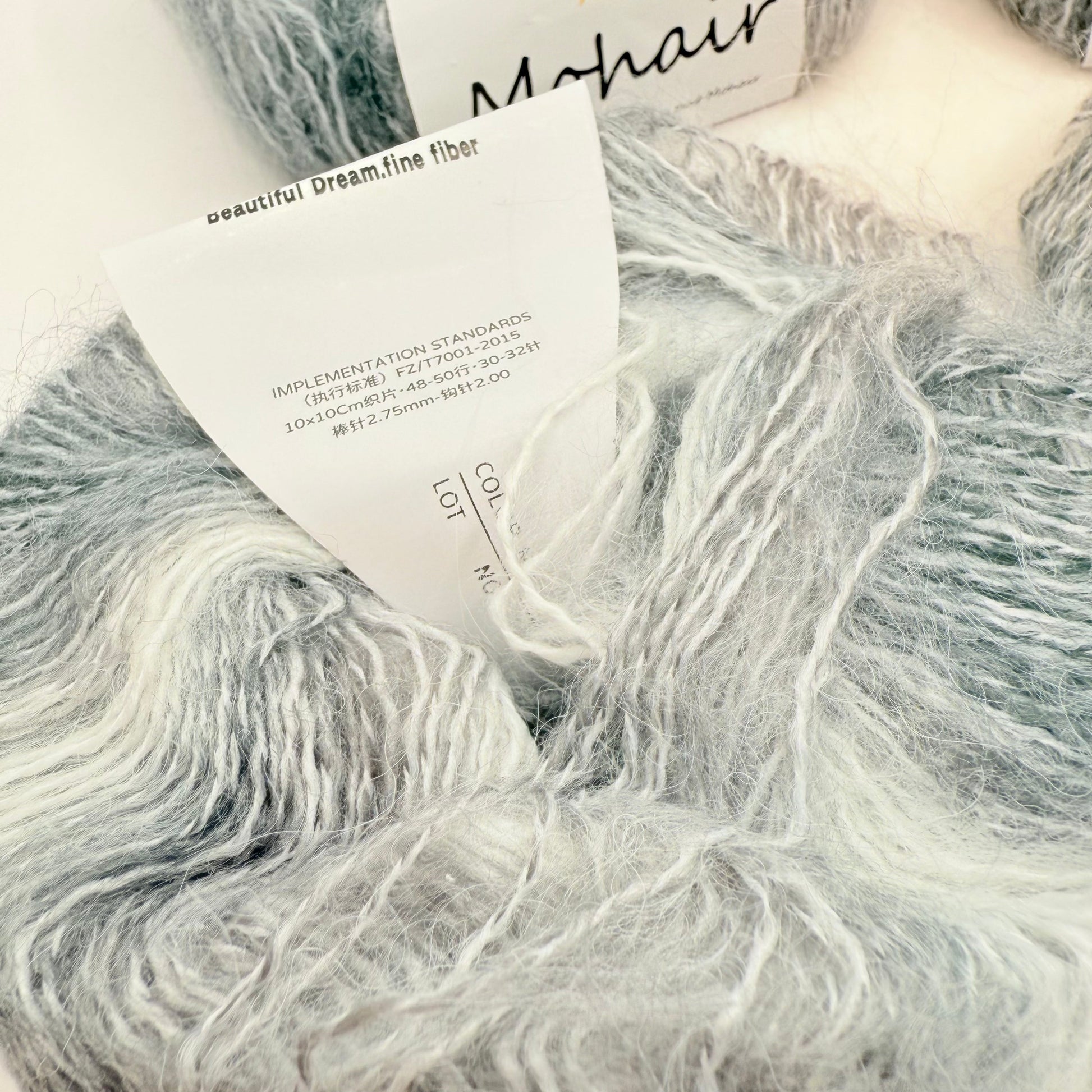 A skein of soft, fluffy mohair yarn in shades of grey and white.