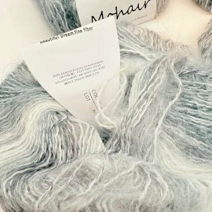 A skein of soft, fluffy mohair yarn in shades of grey and white.