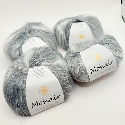 Four skeins of soft, fluffy gray and white variegated mohair yarn.