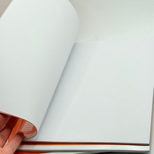 A blank, open notebook with a curved page and an orange spine.